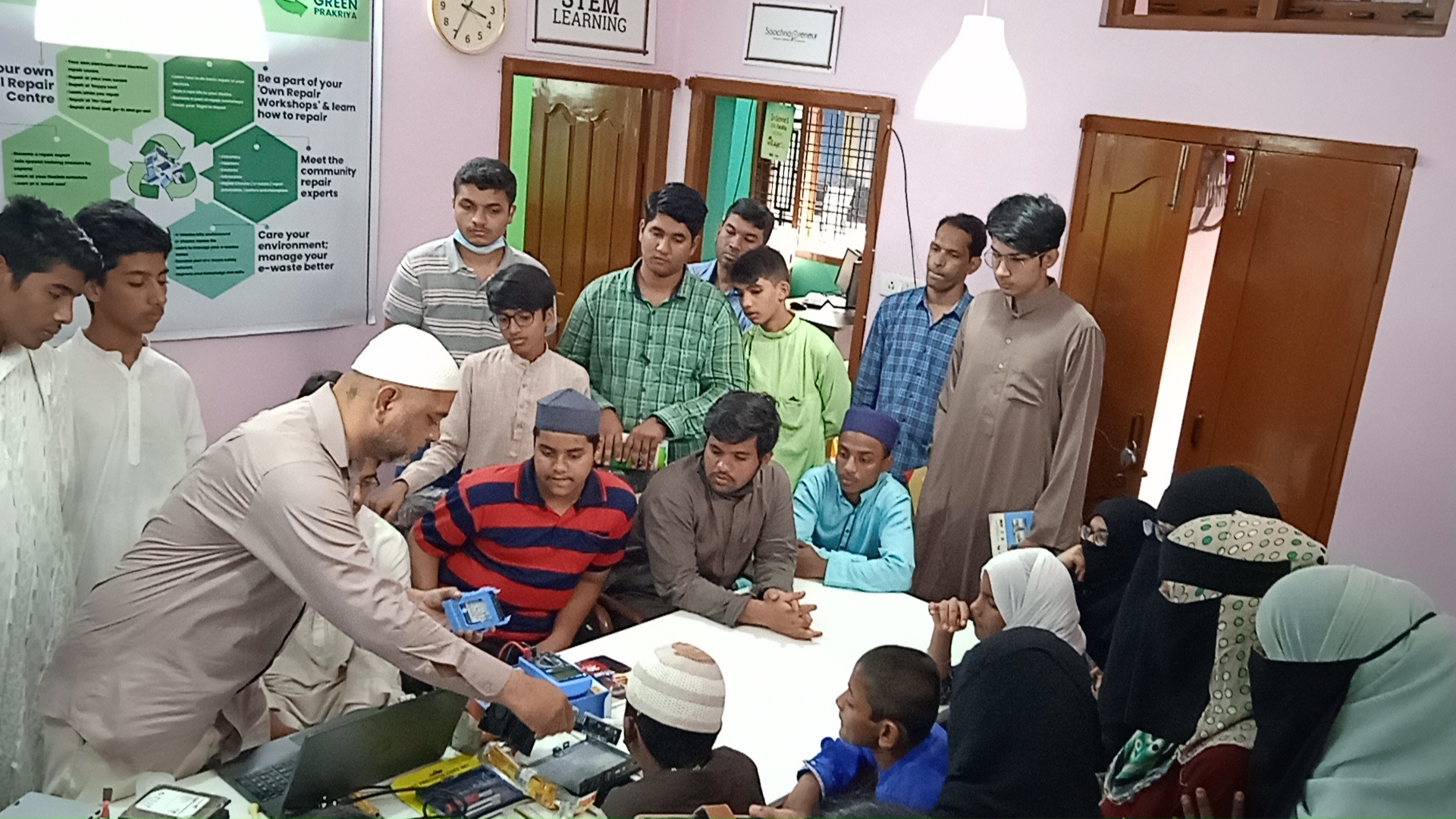 Image of trainer showing a group of youths how to repair various electronic devices. Photo courtesy of DEF.