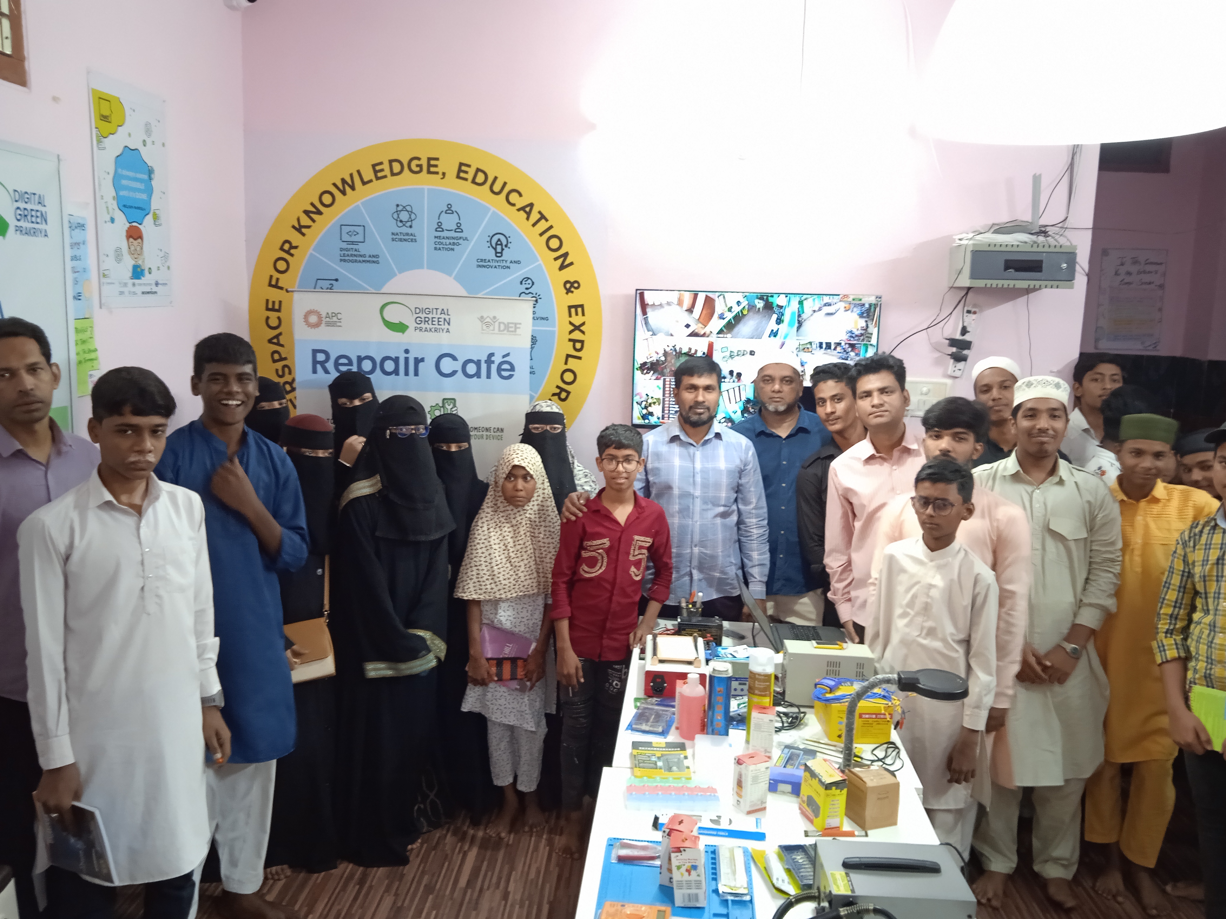 Image of repair cafe participants standing in front of workshop signs. Photo courtesy of DEF.