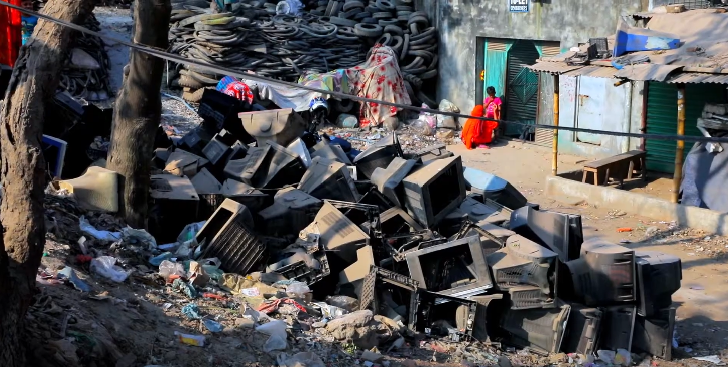 Image: E-waste dumped in large piles around homes and trees. Photo courtesy of VOICE.