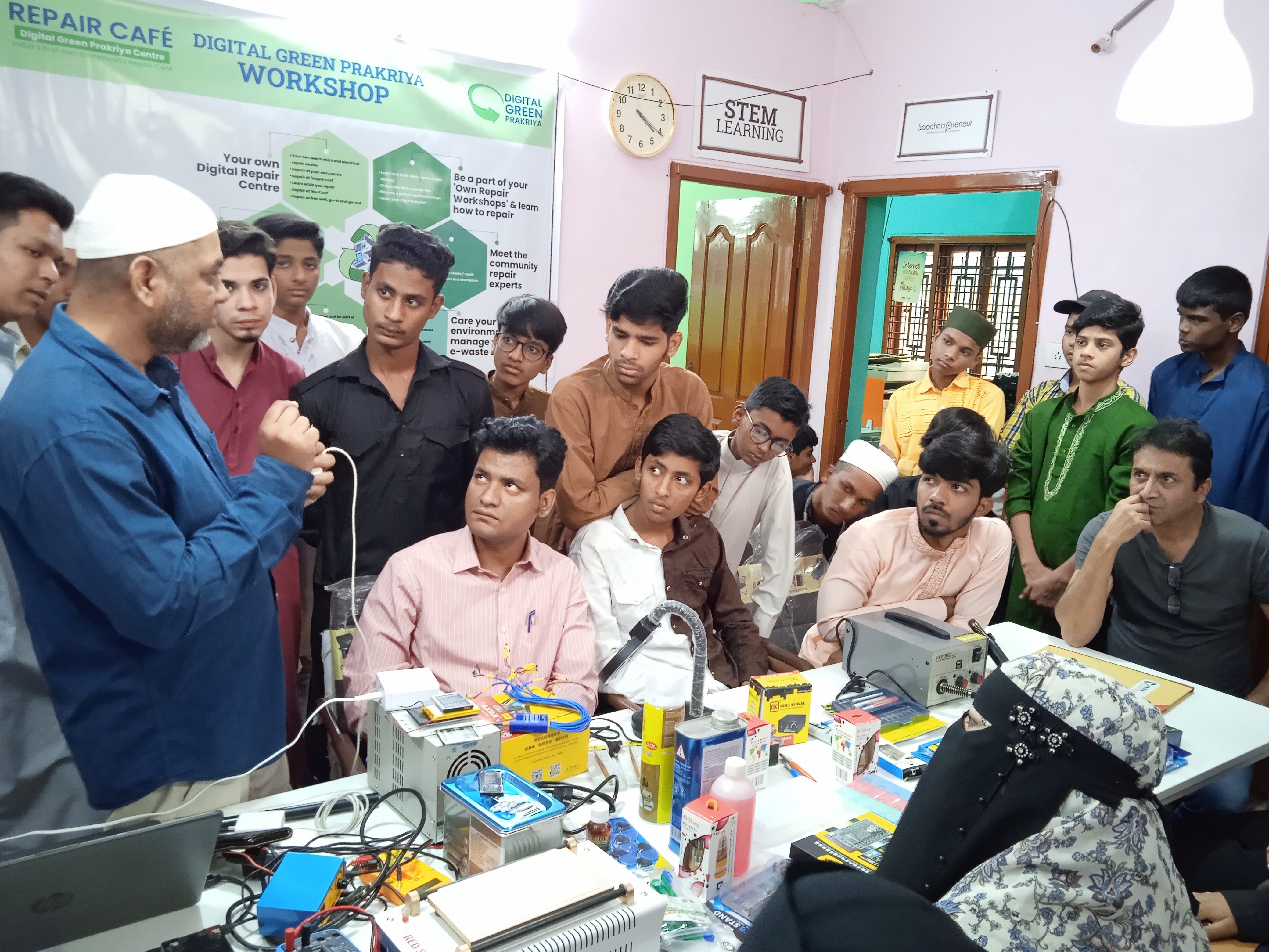 Image of trainer showing a group of youths how to repair various electronic devices. Photo courtesy of DEF.