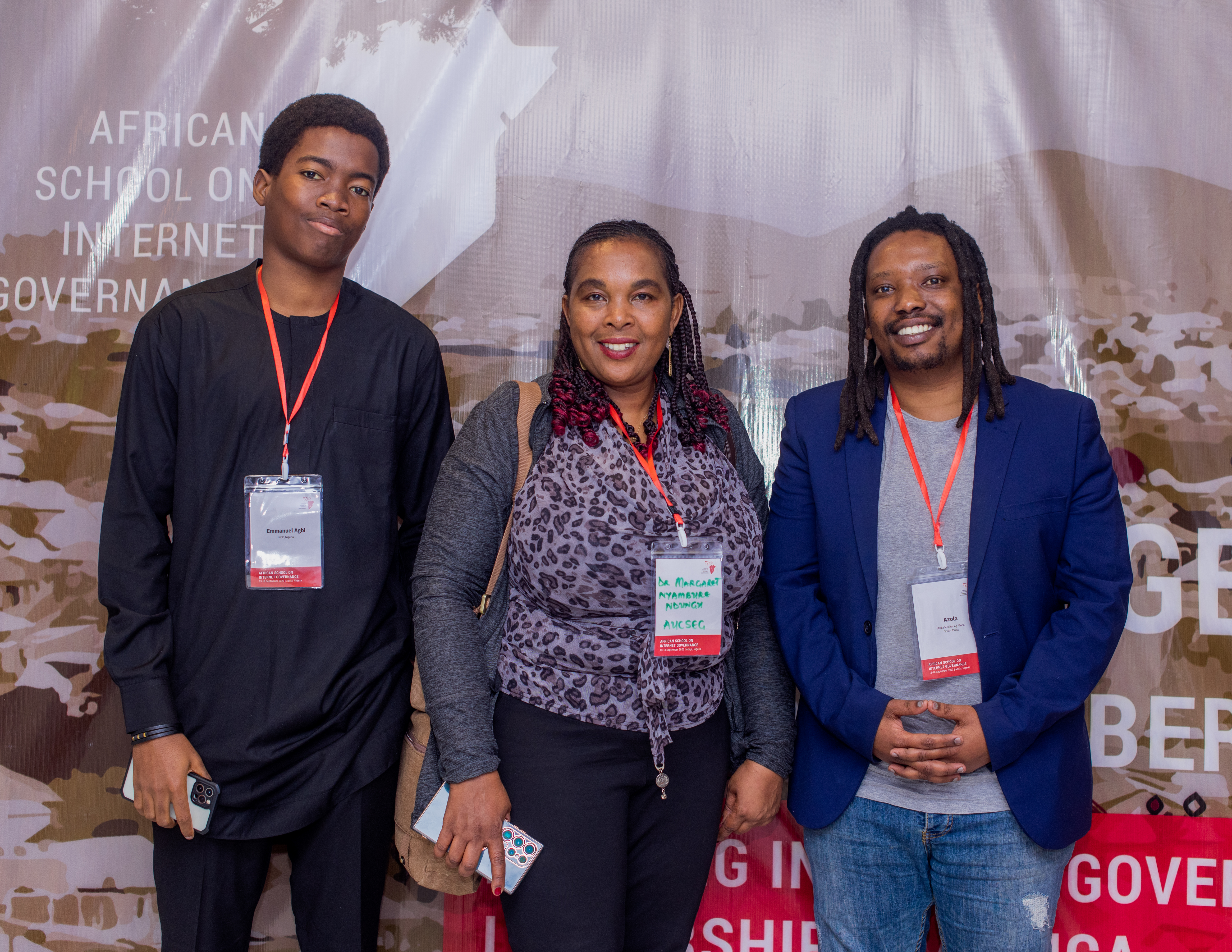 Image of three AfriSIG 2023 fellows standing in front of an event sign.