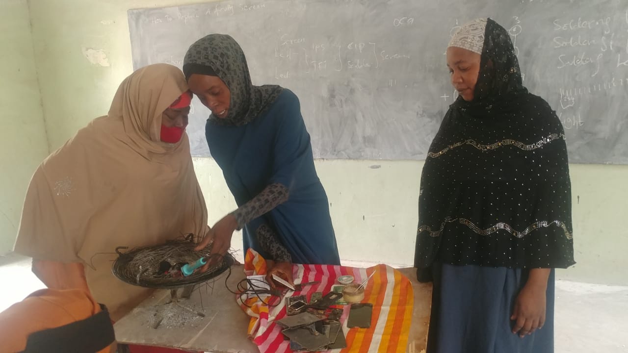 Women gather during a mobile handset repair workshop hosted by CITAD.