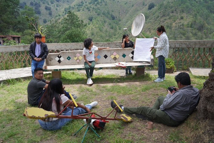 Seven people gather around an antenna during an outdoor activity.