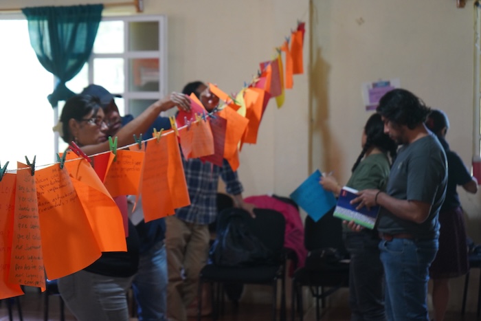 Participants hang orange sheets with notes on a clothesline during an activity.