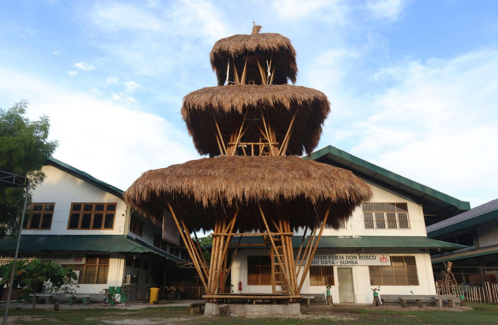 A bamboo tower in front of two buildings