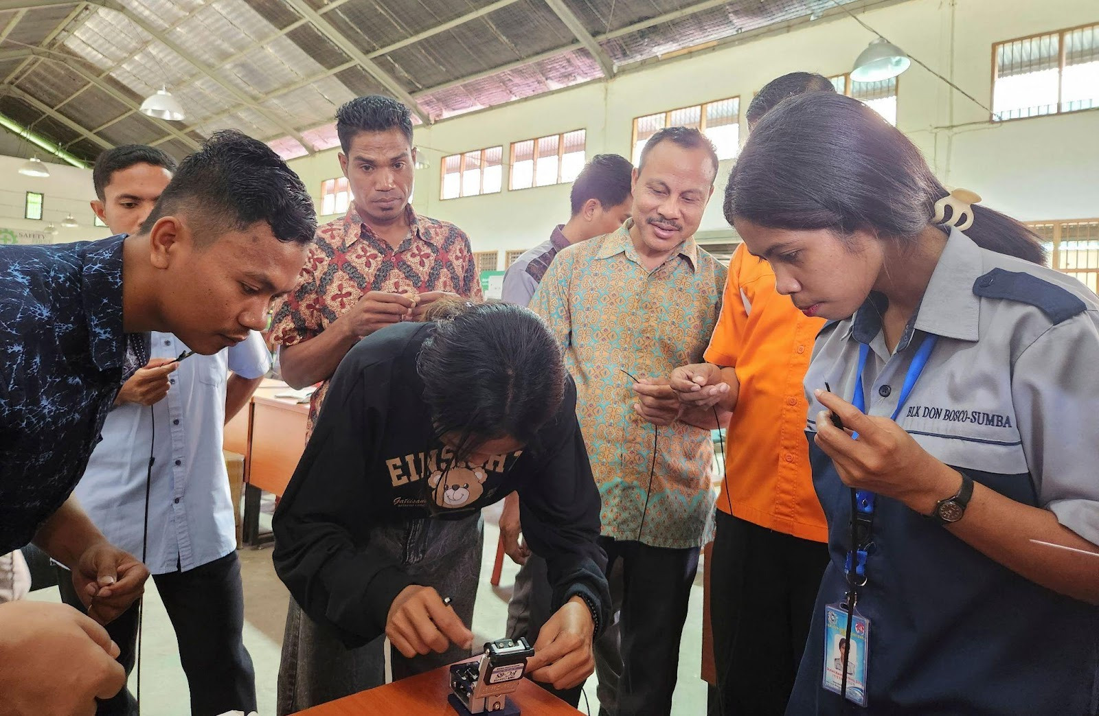 Aa group of people holding cables and one perons in the centre of the group working a very small device