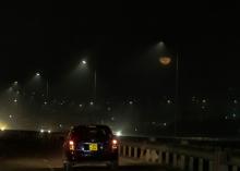 A car travels along a dimly lit road at night in Kampala, Uganda’s capital.