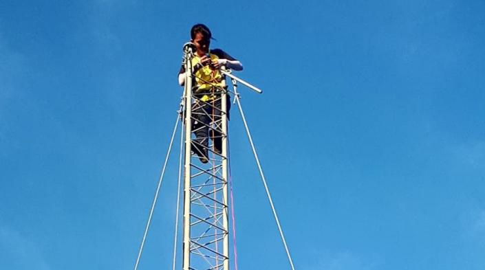 Image description: A person high up on a communications tower. Image source: Village Base Station Project, University of the Philippines